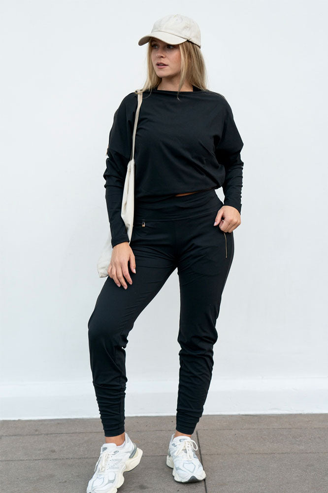 Wijde mouwen en een rechte zoom aan de top, gedragen met een broek, pet en witte katoenen tas.