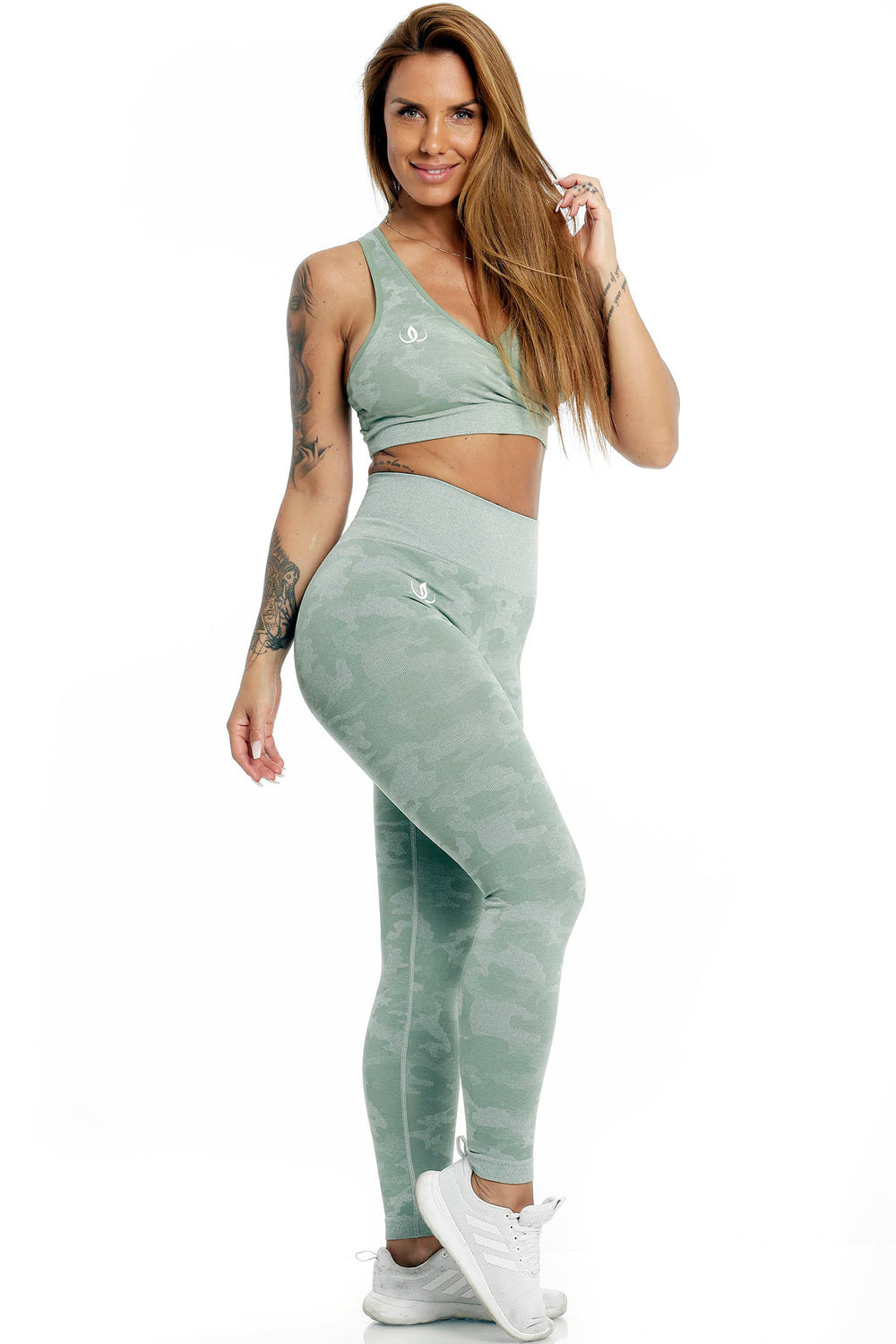Het model staat in de mintgroene top en een legging met camouflageprint, met witte schoenen.