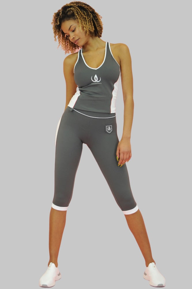 De caprilegging in het grijs heeft een wit schildlogo op de dij en witte randen onderaan. Het model draagt een grijze top.