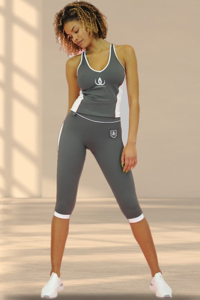 Het model draagt de donkergrijze top bij een grijze caprilegging met witte rand bij de knie.