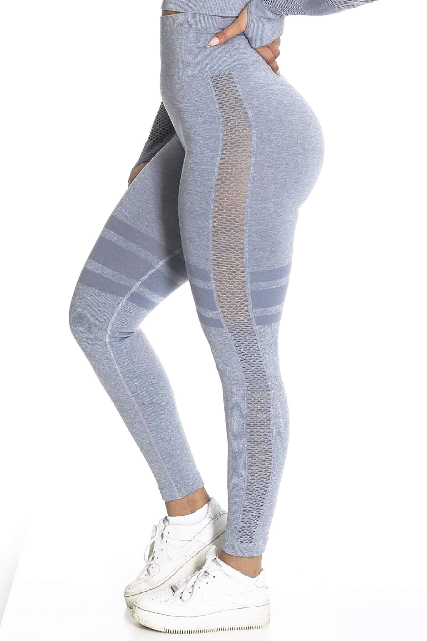 Zijkant van de grijze legging met meshinzet en gestreepte banden, boven witte sneakers.