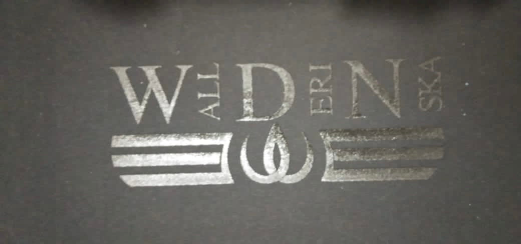 Het logo gedrukt in dezelfde donkere tint als de stof, met letters en twee strepen rond het symbool.