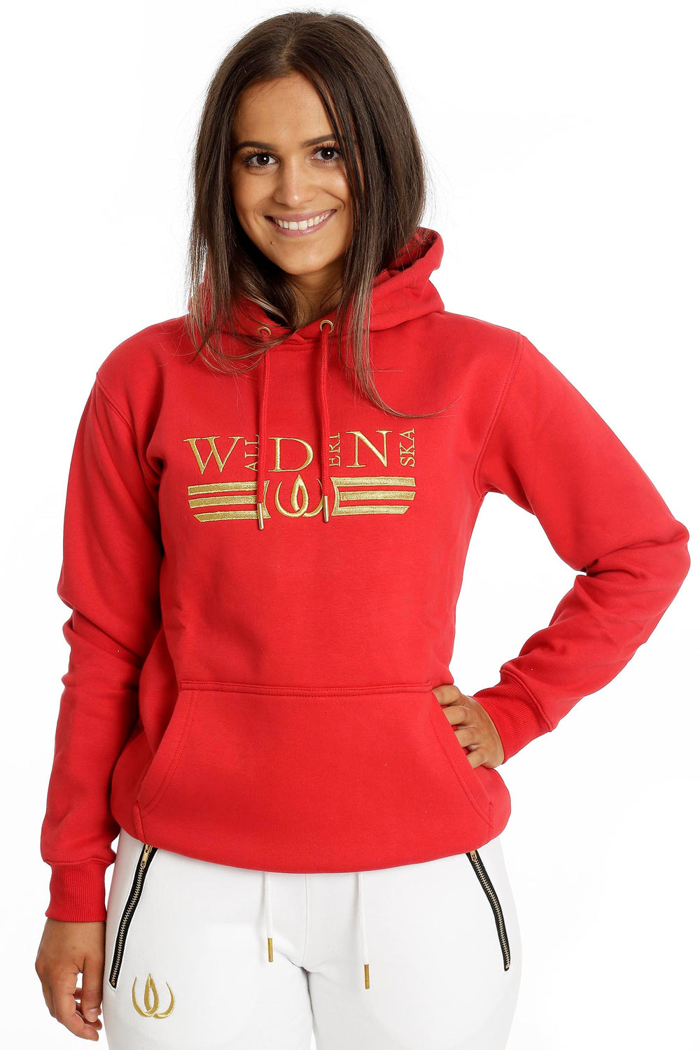 Het model draagt de rode hoodie met gouden borduursel en kangoeroezak met Deluxe Joggers wit.