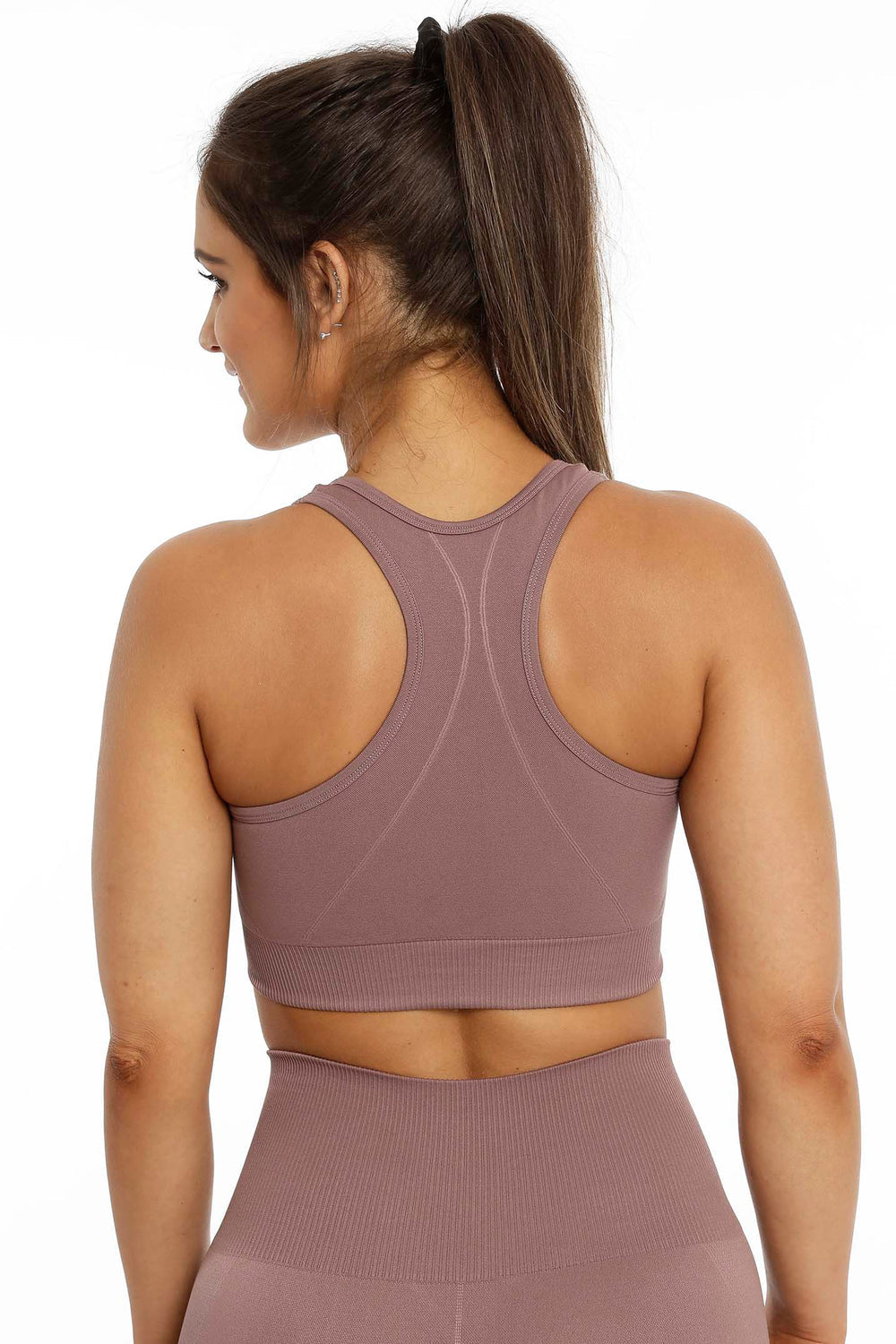 Racerback en geribde rand onderaan de rosébruine top, met een bijpassende legging eronder.