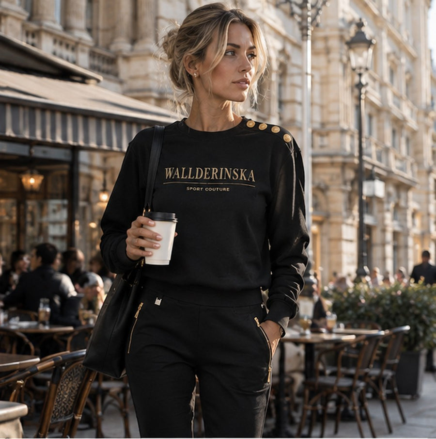 Edge Gold Button sweater en Edge Casual Zip broek met koffie buiten een café in de stad.